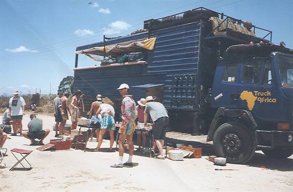 Travelers camping beside a blue Africa overland tour truck