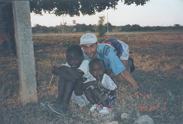 Tourist with two children sitting on dry grass under a tree
