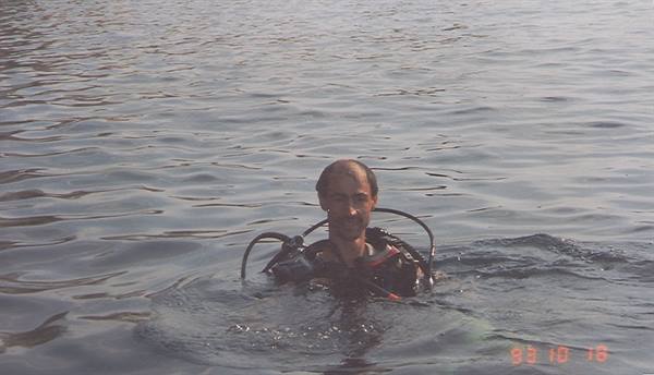 Diver in full scuba gear surfacing in calm water