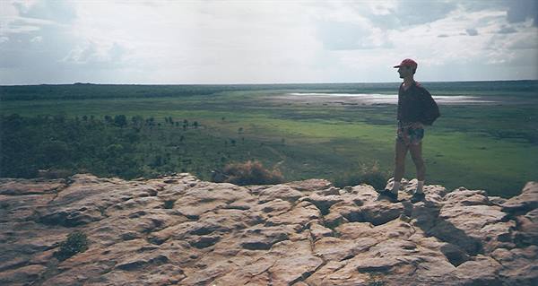Boy in red cap standing on limestone rock above green wetland