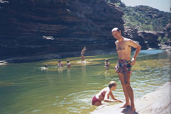 Swimmers in Karijini gorge pool, man in swim trunks on rock