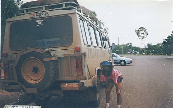Girl beside a Toyota Land Cruiser van with spare wheel, windmill in background