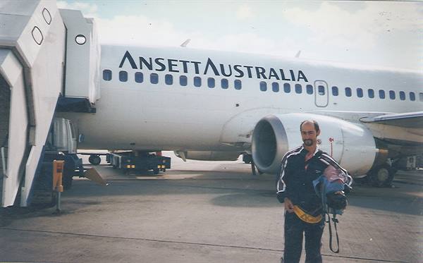 Traveler holding a baby in front of an Ansett Australia Boeing on the apron