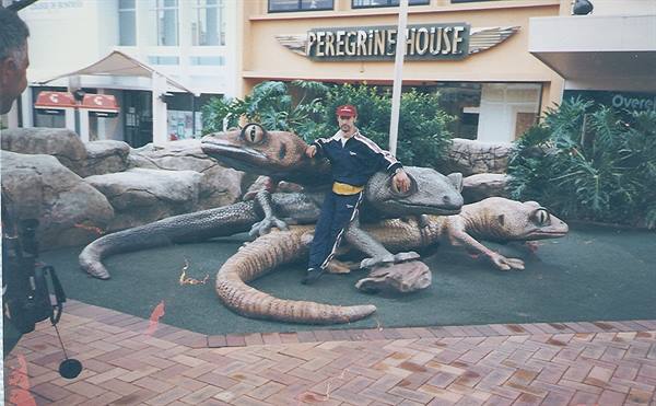 Man in tracksuit leaning on giant lizard statues in front of Peregrine House