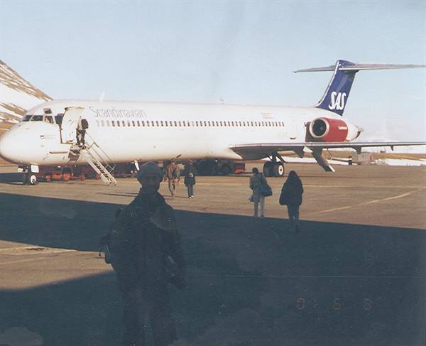 SAS plane parked with open stairs, passengers walking on snowy tarmac