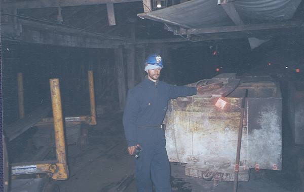 Miner in blue helmet next to an ore cart underground