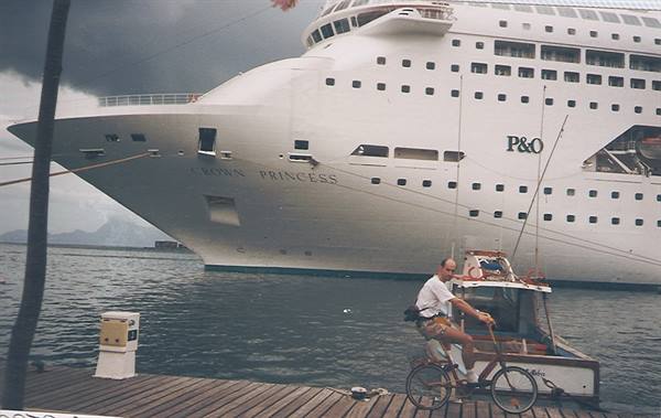 Man cycling on wooden pier in front of the P&O Crown Princess ship