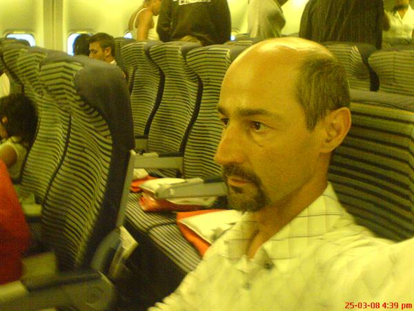 Bald man in light shirt seated among striped airplane seats