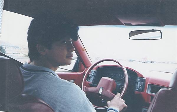 Young man driving a car with red dashboard and dark leather interior