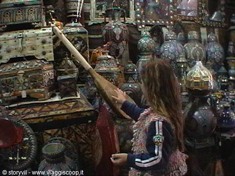 Girl touching a traditional drill among handcrafted metal objects