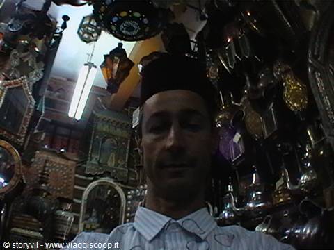 Man in hat among metal lanterns and mirrors inside Marrakech souk