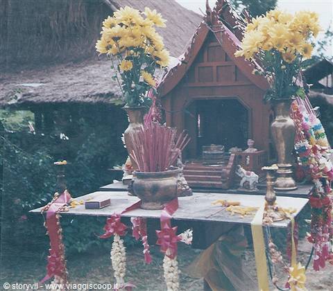 Wooden spirit house with yellow chrysanthemums, incense sticks and flower garlands