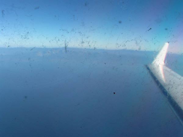airplane wing through a smudged window above the clouds