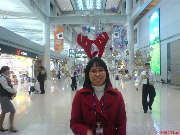 Girl wearing red reindeer antlers in decorated Incheon terminal