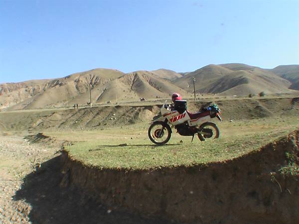 Motorcyclist with pink helmet on enduro bike among arid hills