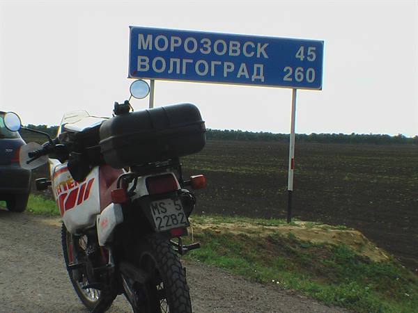 Touring motorcycle parked beside the road sign: Morozovsk 45, Volgograd 260