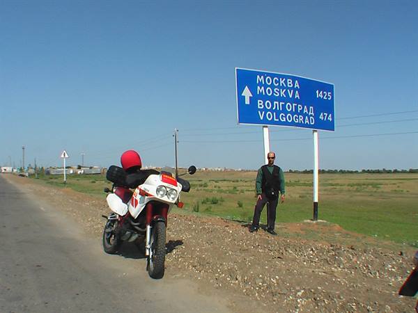 Motorbike with red seat beside road sign pointing to Moskva and Volgograd
