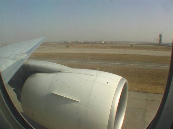 Aircraft engine and wing seen through the window, plane taxiing on runway