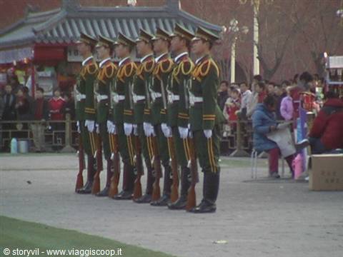Soldiers in green uniforms with rifles standing in formation at Tiananmen Square