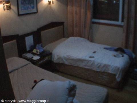 Hotel room with two single beds, warm lamp light