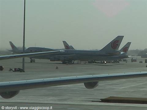 Air China planes parked on airport tarmac, wing in foreground, hazy light