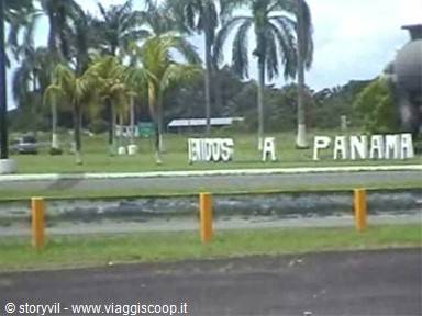 Bienvenidos a Panamá sign among palm trees, green field and yellow posts