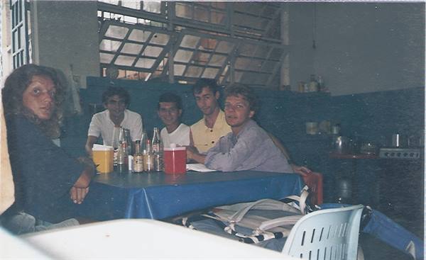 Five friends sitting at a blue-clothed table inside a kitchen