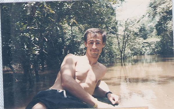Shirtless guy lying on a canoe in an Amazonian river