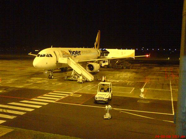 Tiger Airways plane with boarding stairs at night on airport tarmac