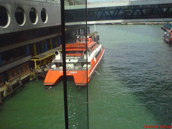 Red ferry moored at the ferry terminal, bridge above green water