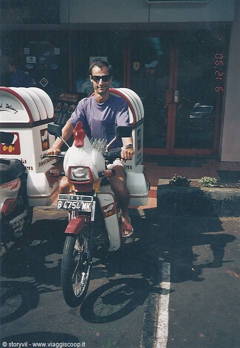 Tourist riding a delivery motorbike with chicken figure, Jakarta plate B 6754 MK