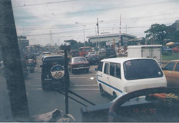 City traffic seen from a bus: white minivan and cars stopped at the light