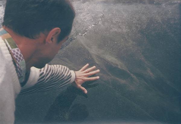 Man places his open hand on a sheet of black ice