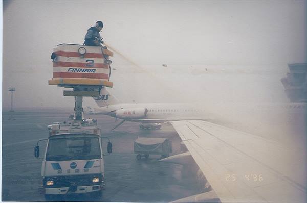 Finnair de-icing truck sprays fluid on the aircraft wing in fog