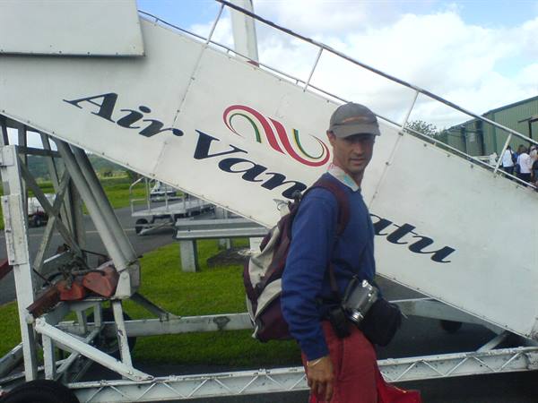 Traveler with backpack and camera in front of Air Vanuatu boarding stairs