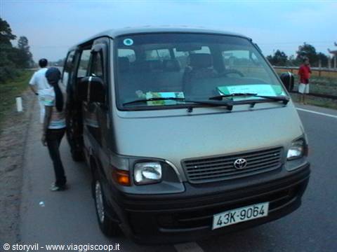 Traveler beside a grey Toyota minibus parked on a rural road