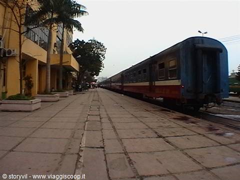 Blue and red train car stopped on track beside empty platform