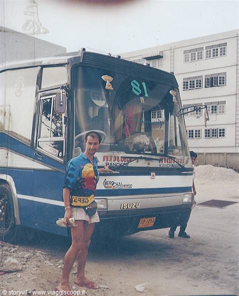 Tourist in Hawaiian shirt in front of a blue Isuzu bus with Thai signs