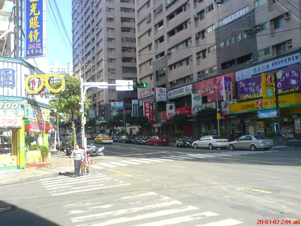 Pedestrians on zebra crossing among colorful signs, scooters and cars