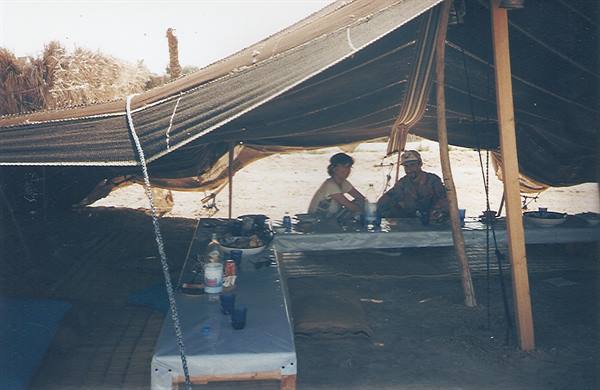 Woman and man seated at a table under a Bedouin tent in the desert