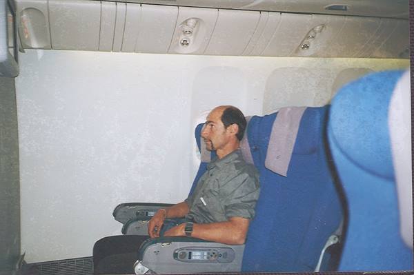 Man sitting next to blue seats inside an airplane cabin