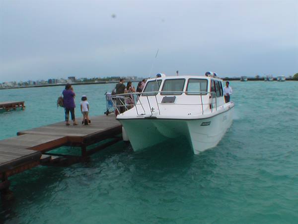 White ferry moored at wooden jetty, passengers disembark into turquoise water