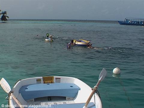 Snorkelers swim near a small boat in a turquoise lagoon