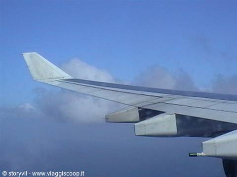 Airplane wing seen from the window above blue clouds