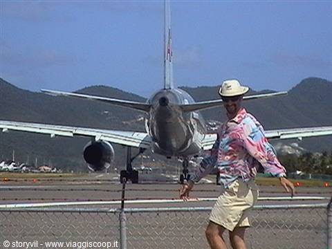 Tourist in hat in front of a departing plane at Maho Beach runway