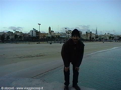 Young man in black hoodie posing on the waterfront by San Vito Lo Capo beach