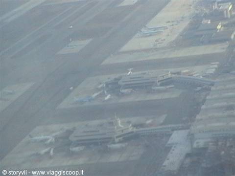 Airplanes parked at airport terminals seen from a taking-off plane