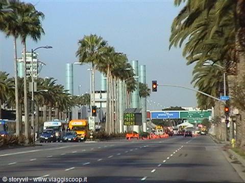 Urban road lined with palm trees, traffic lights and cars, Los Angeles