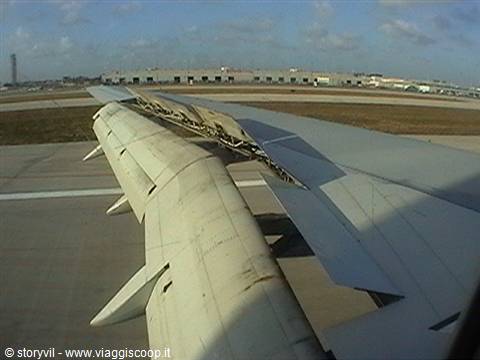 Aircraft wing and engine with spoilers deployed, taxiing on the airport runway