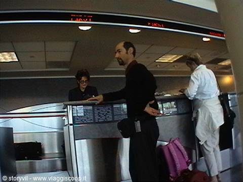 Man with purple suitcase at Linate airport check-in counter